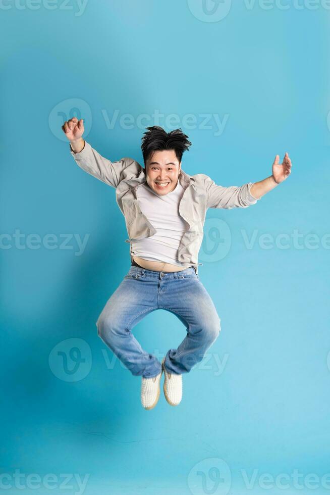 Full body image of Asian man posing on blue background photo