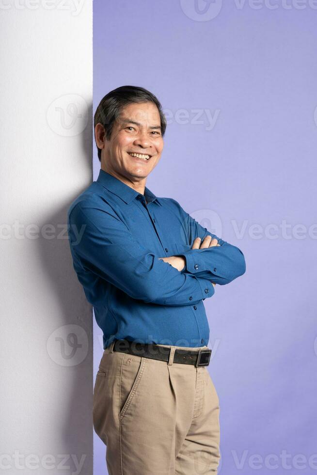 retrato de medio Envejecido asiático negocio hombre posando en púrpura antecedentes foto