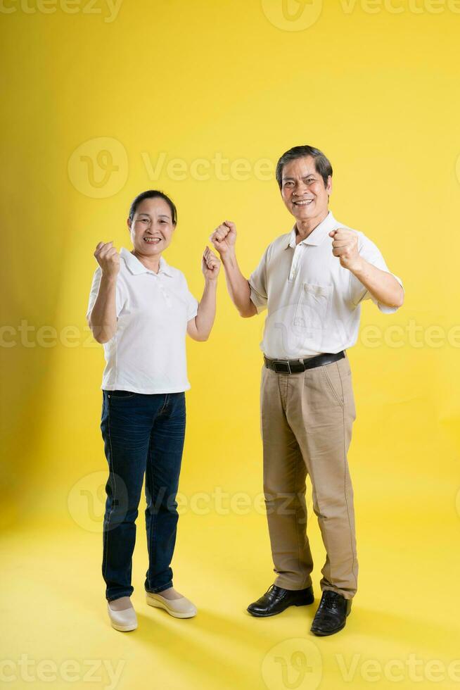 portrait of middle aged asian couple posing on yellow background photo