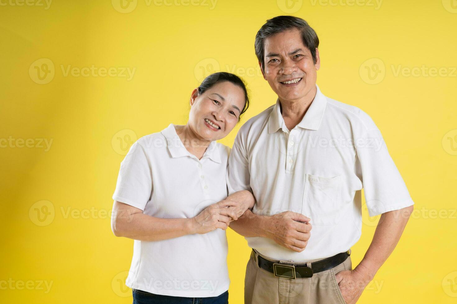 portrait of middle aged asian couple posing on yellow background photo