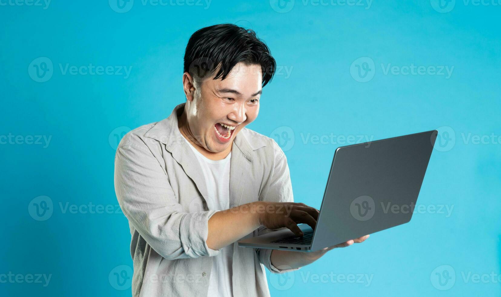 Image of Asian man using laptop on blue background photo