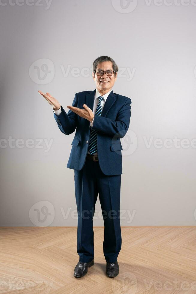 Portrait of an elderly Asian businessman, posing on a blue background photo