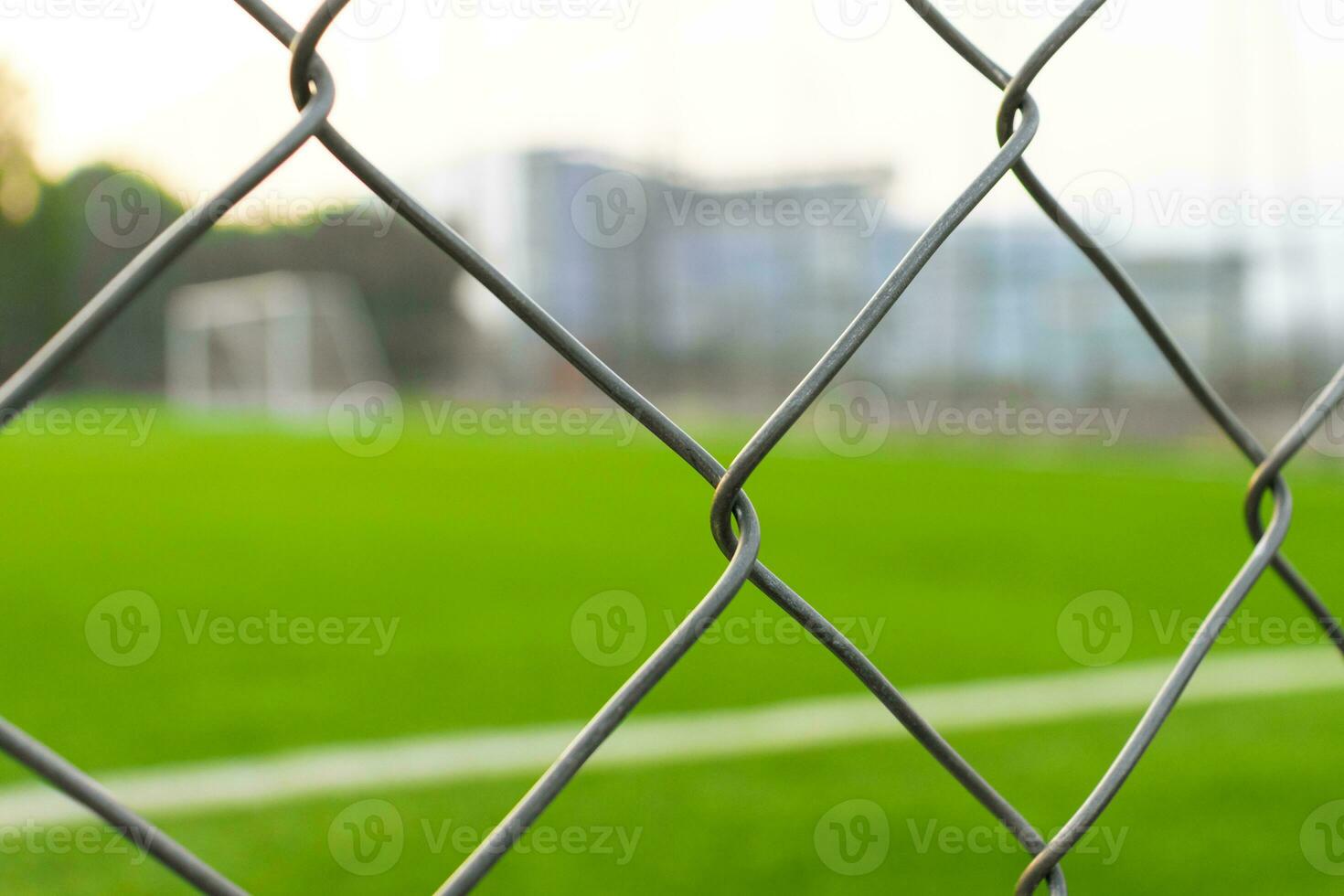 A soccer field view from outside the fence, focusing on the fence. After some edits. photo
