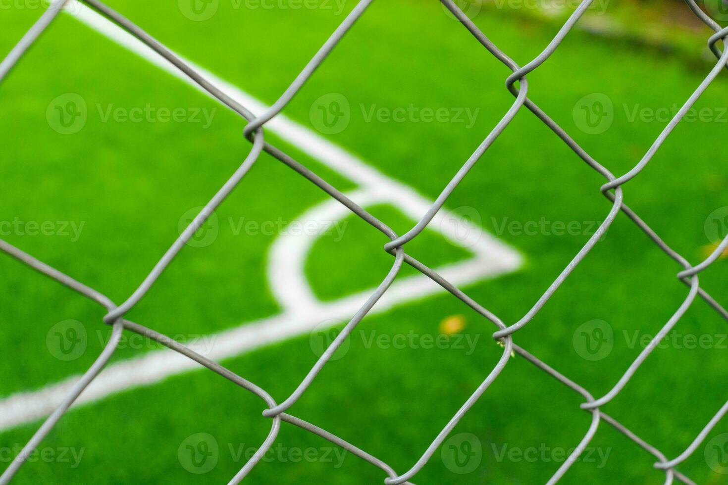 A soccer field view from outside the fence, focusing on the fence. After some edits. photo