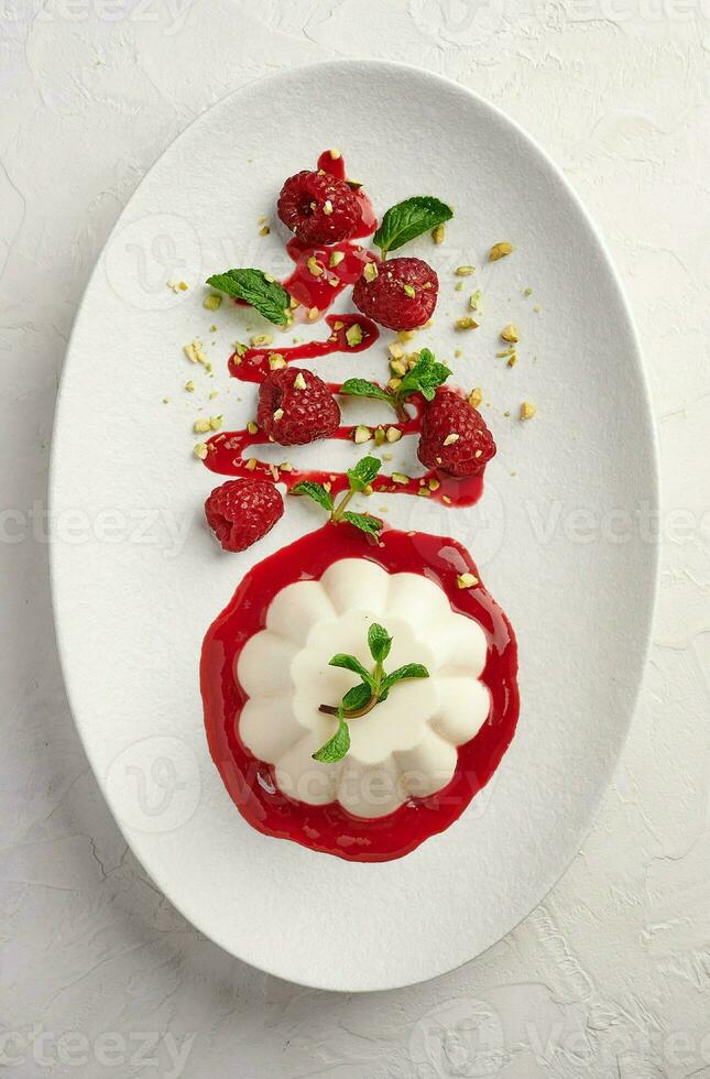 Vertical orientation panna cotta with raspberry syrup, pistachios, berries and mint photo