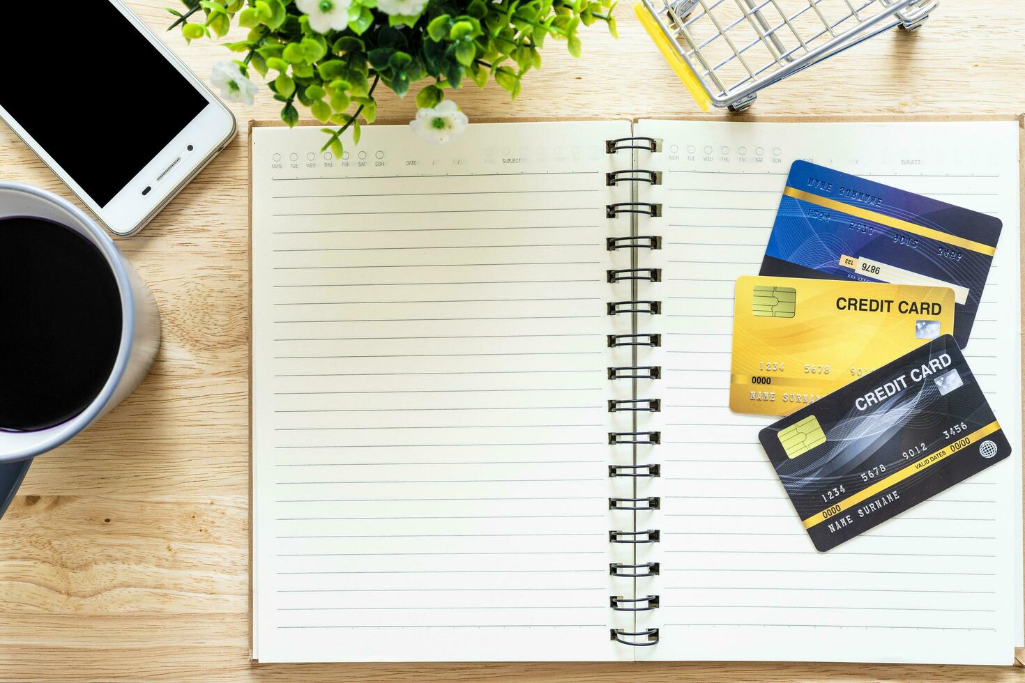 Credit cards,notebook,flower pot tree,smartphone,Shopping cart and coffee cup on wooden background,Online banking Concept,Top view office table. photo