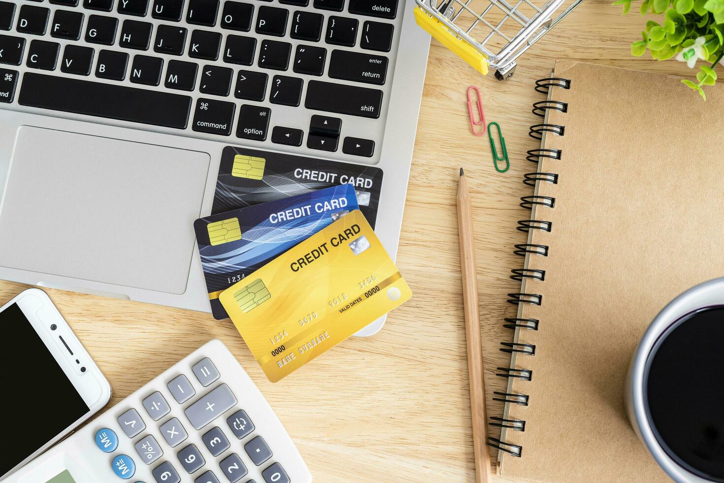 Credit card in Shopping cart with laptop,notebook,flower pot tree,smartphone and calculator on wooden background, Online banking Concept,Top view office table. photo