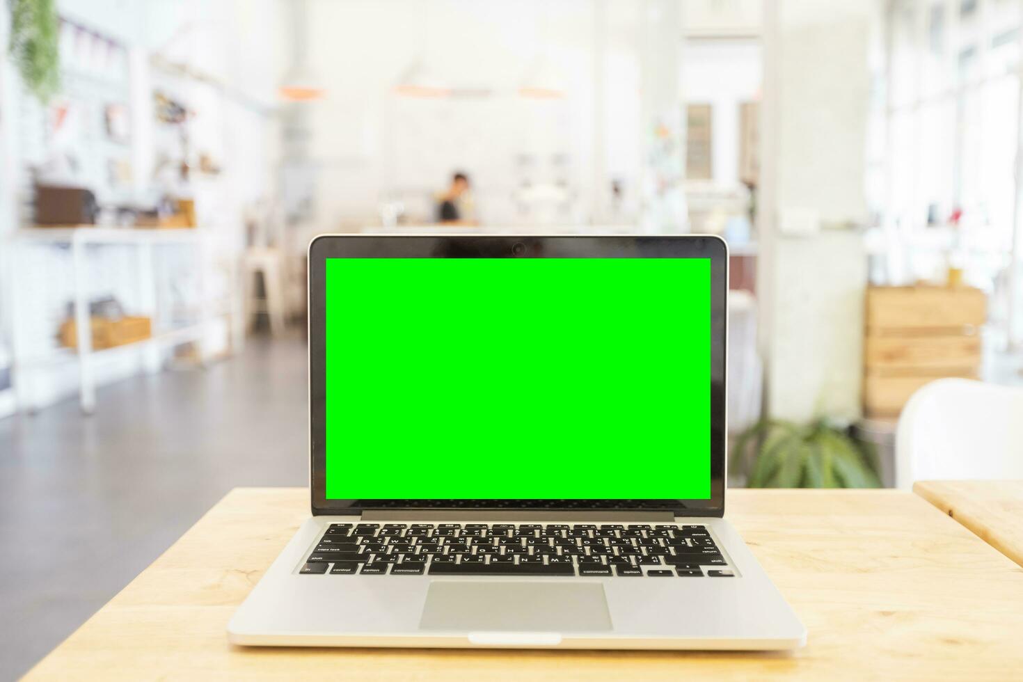 Mockup image of laptop with blank Green screen on wooden table of In the coffee shop. photo