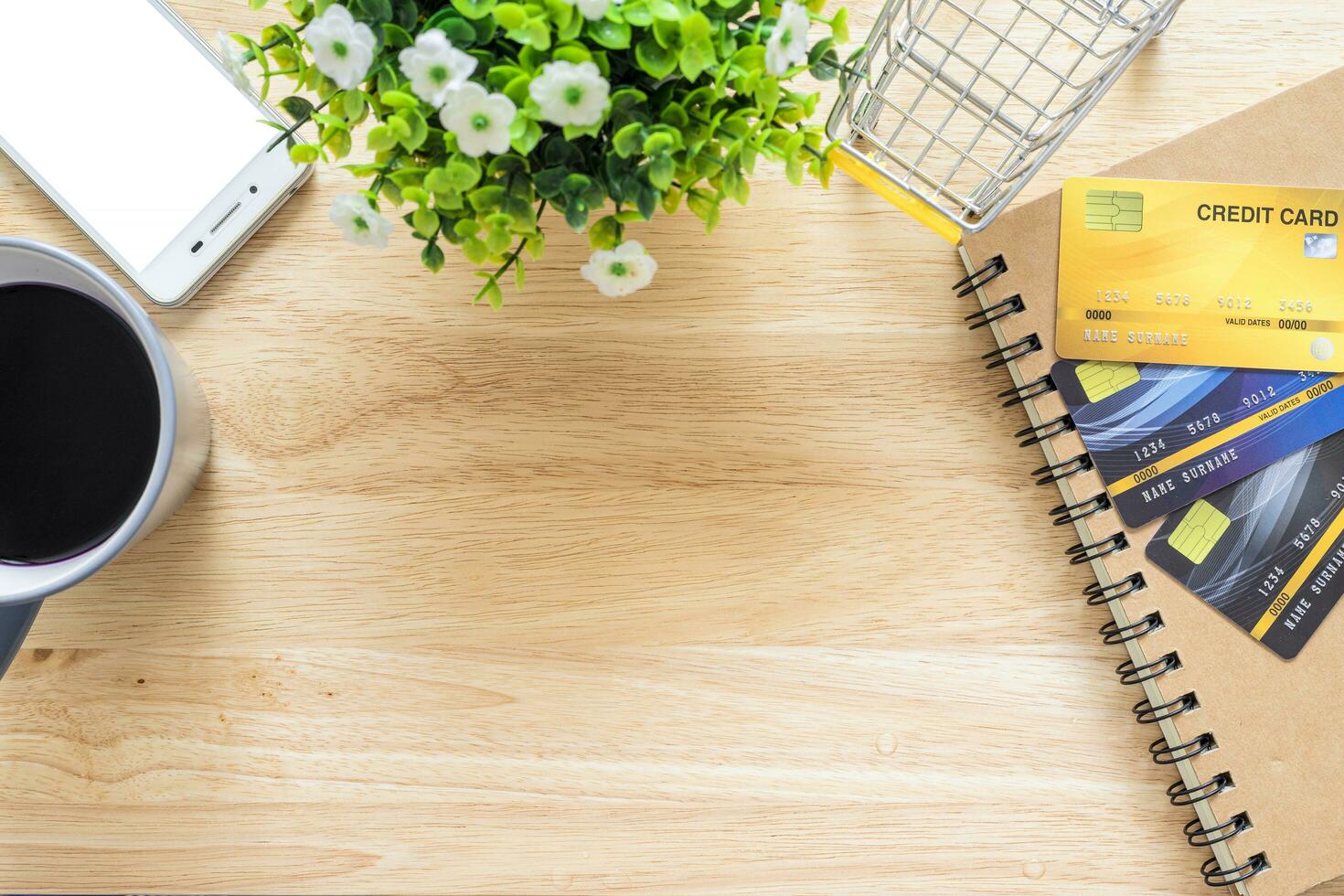 Credit cards,notebook,flower pot tree,smartphone,Shopping cart and coffee cup on wooden background,Online banking Concept,Top view office table. photo