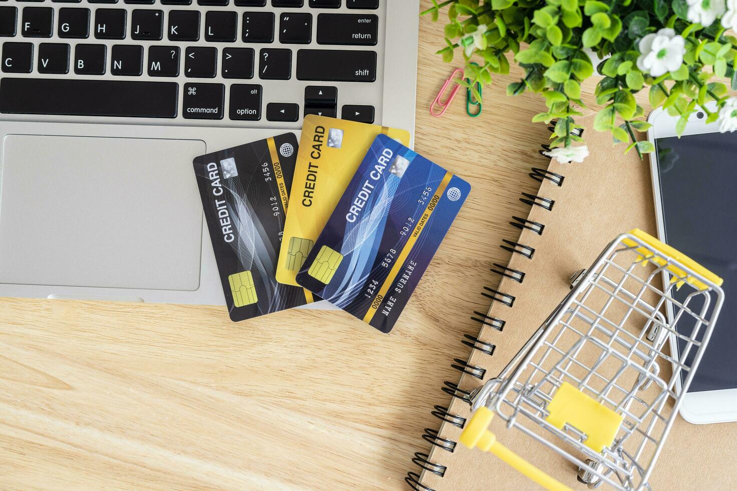 Credit card in Shopping cart with laptop,notebook,flower pot tree on wooden background, Online banking Concept,Top view office table. photo