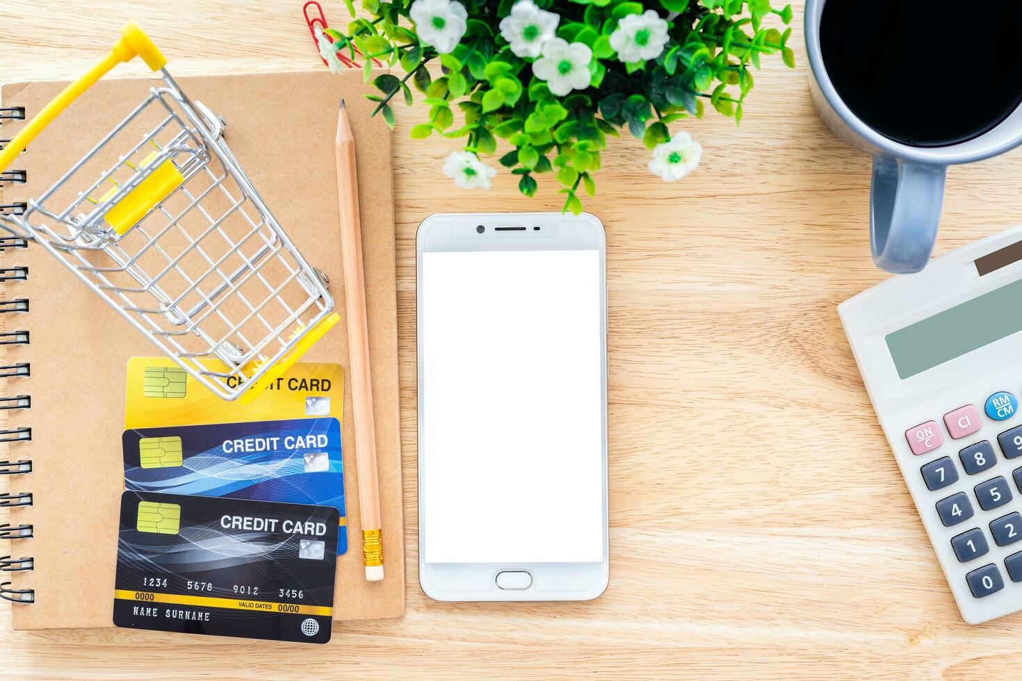 Credit cards,notebook,flower pot tree,smartphone,Shopping cart and coffee cup on wooden background,Online banking Concept,Top view office table. photo