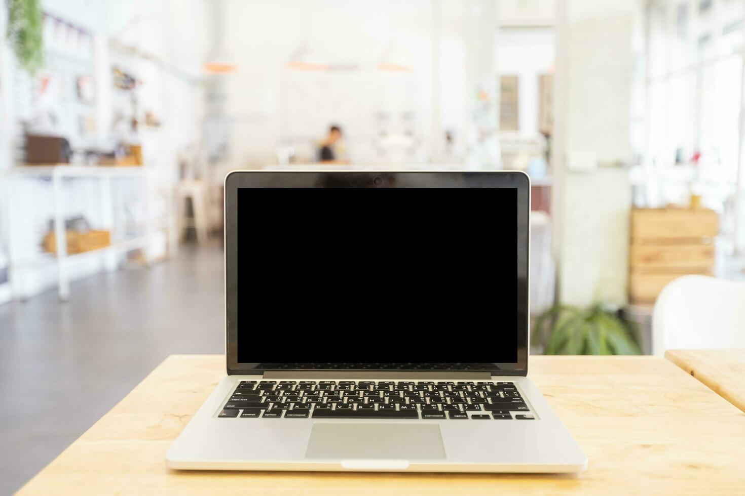Mockup image of laptop with blank Black screen on wooden table of In the coffee shop. photo