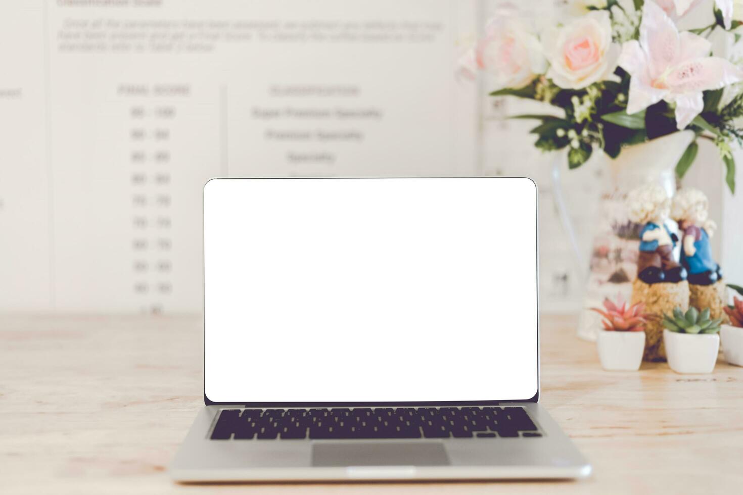 Mockup image of laptop with blank white screen on wooden table of In the coffee shop. photo