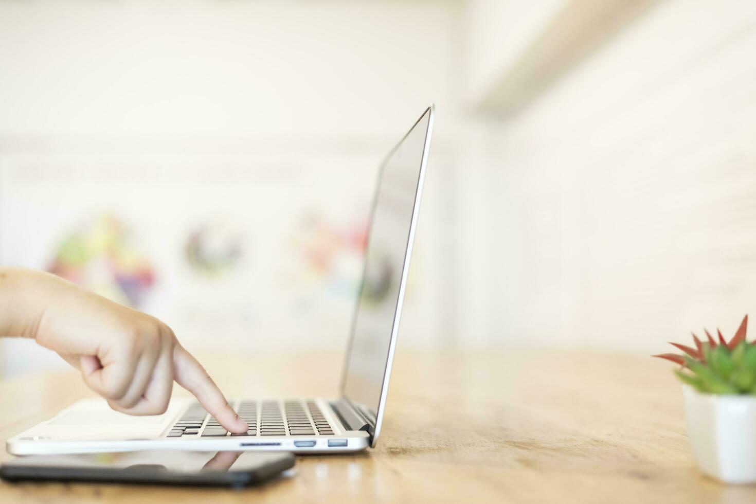 Close-up of business female working hands typing on a laptop keyboard with smartphone in coffee shop like the background photo