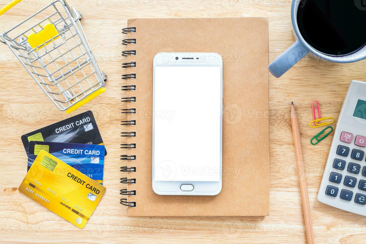 crédito Tarjetas,cuaderno,flor maceta Árbol,smartphone,compras carro y café taza en de madera fondo, en línea bancario concepto,arriba ver oficina mesa. foto