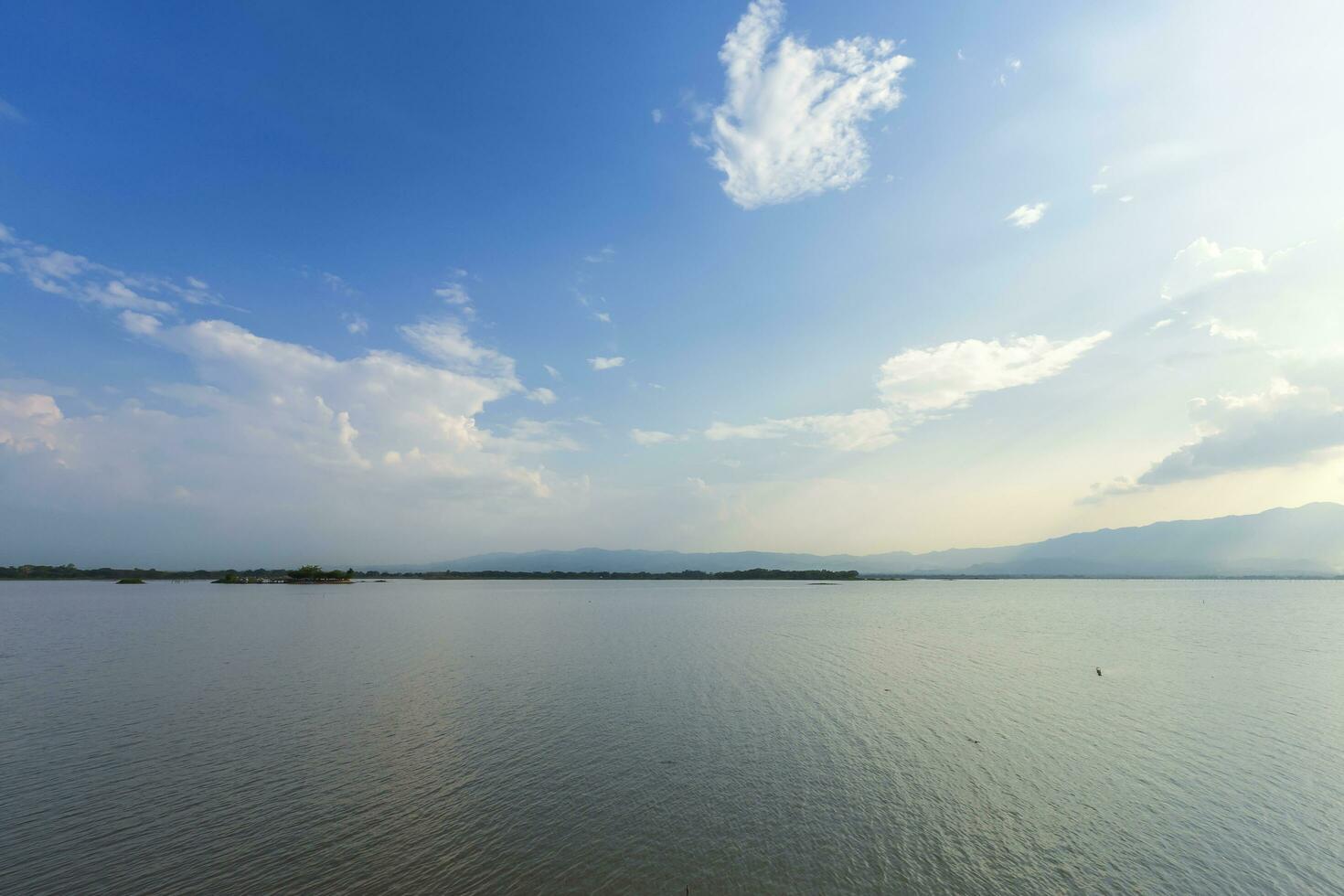 landscape of sunshine on lake or large swamp and mountains and blue dramatic sky with cloud at sunset at Kwan Phayaoin Phayao Province, northern Thailand. photo