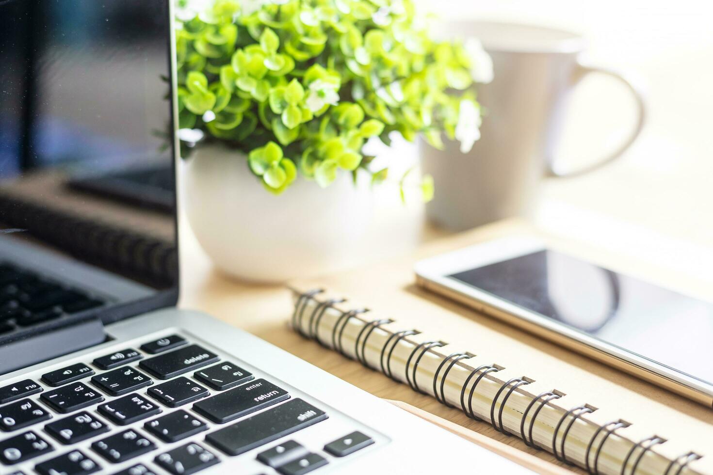 laptop with smartphone on notebook,a pencil and flower pot tree on wooden background,Top view office table. photo