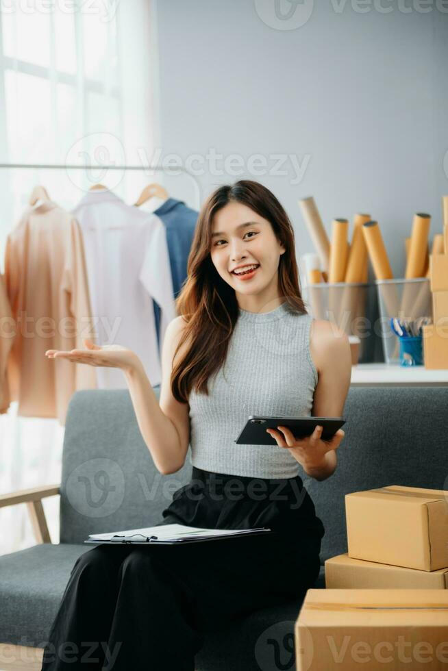 Asian lady blogger showing clothes in front of the camera to recording vlog video live streaming at her shop. photo