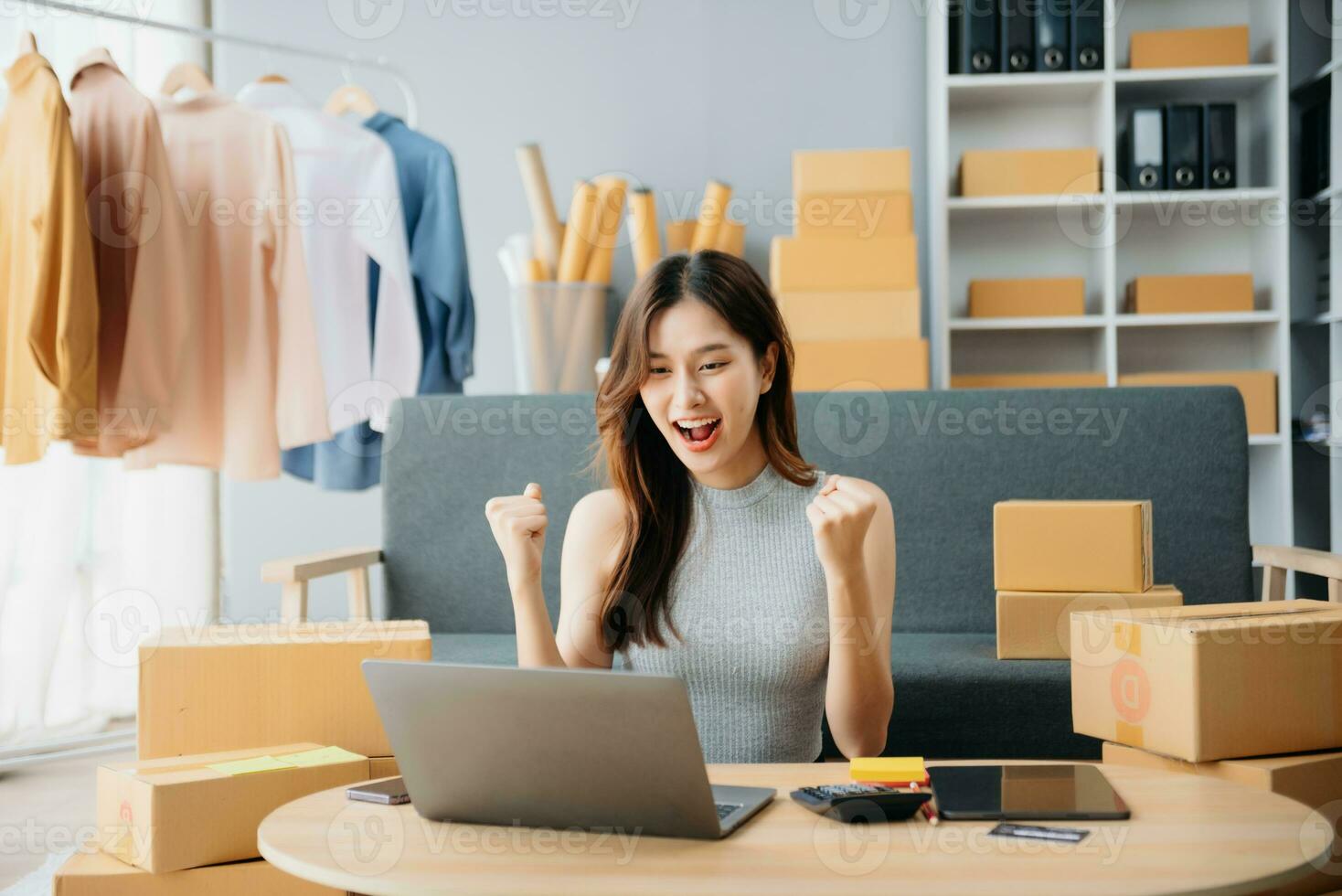 Young woman running online store Startup small business SME, using smartphone or tablet taking receive and checking online purchase shopping photo