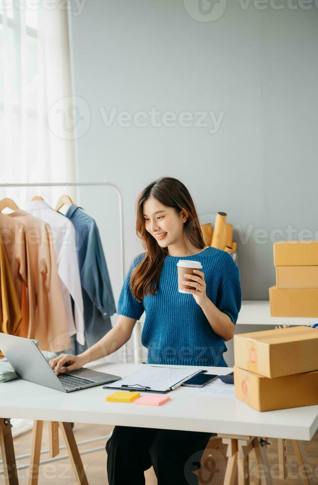 Young woman running online store Startup small business SME, using smartphone or tablet taking receive and checking online purchase shopping photo