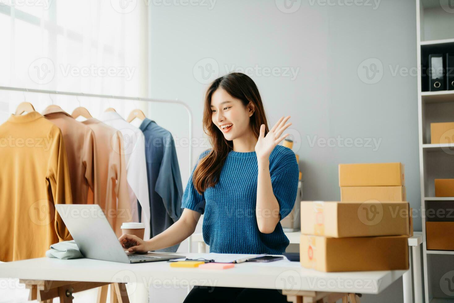 Asian lady blogger showing clothes in front of the camera to recording vlog video live streaming at her shop. photo