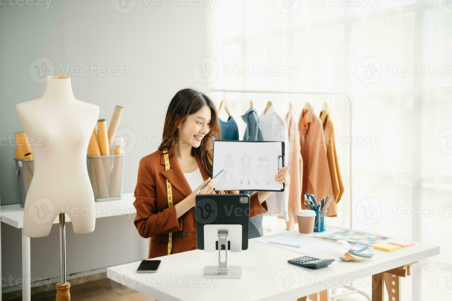 Diverse female fashion designers at work with tailor centimeters on necks and holds tablet and smartphone. independent creative design photo