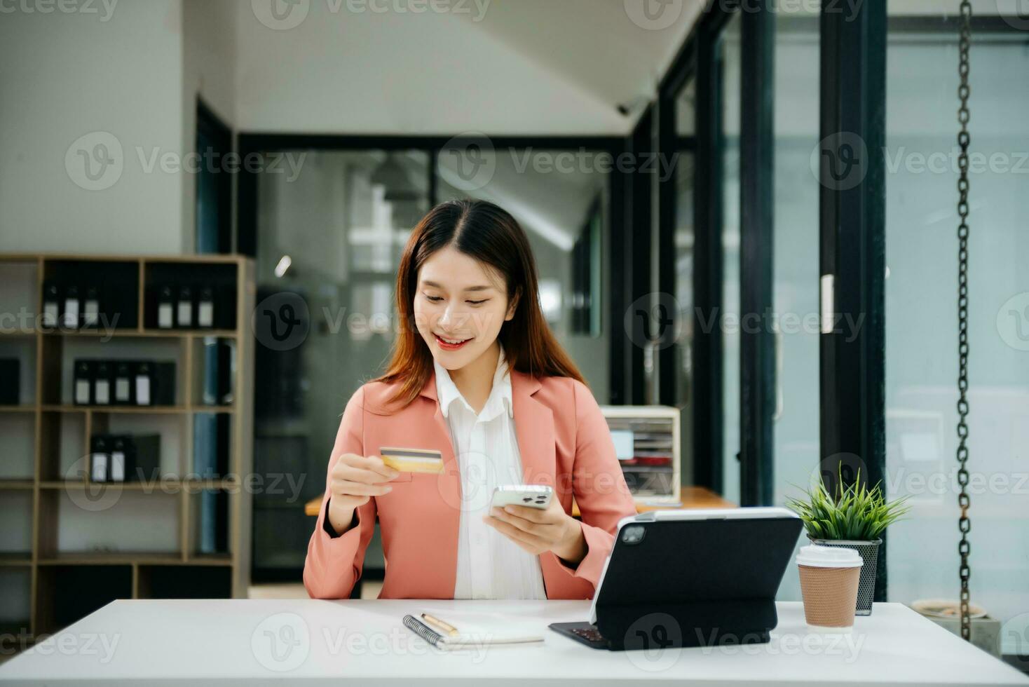 Woman using smart phone for mobile payments online shopping, omni channel, sitting on table, virtual icons graphics interface screen photo