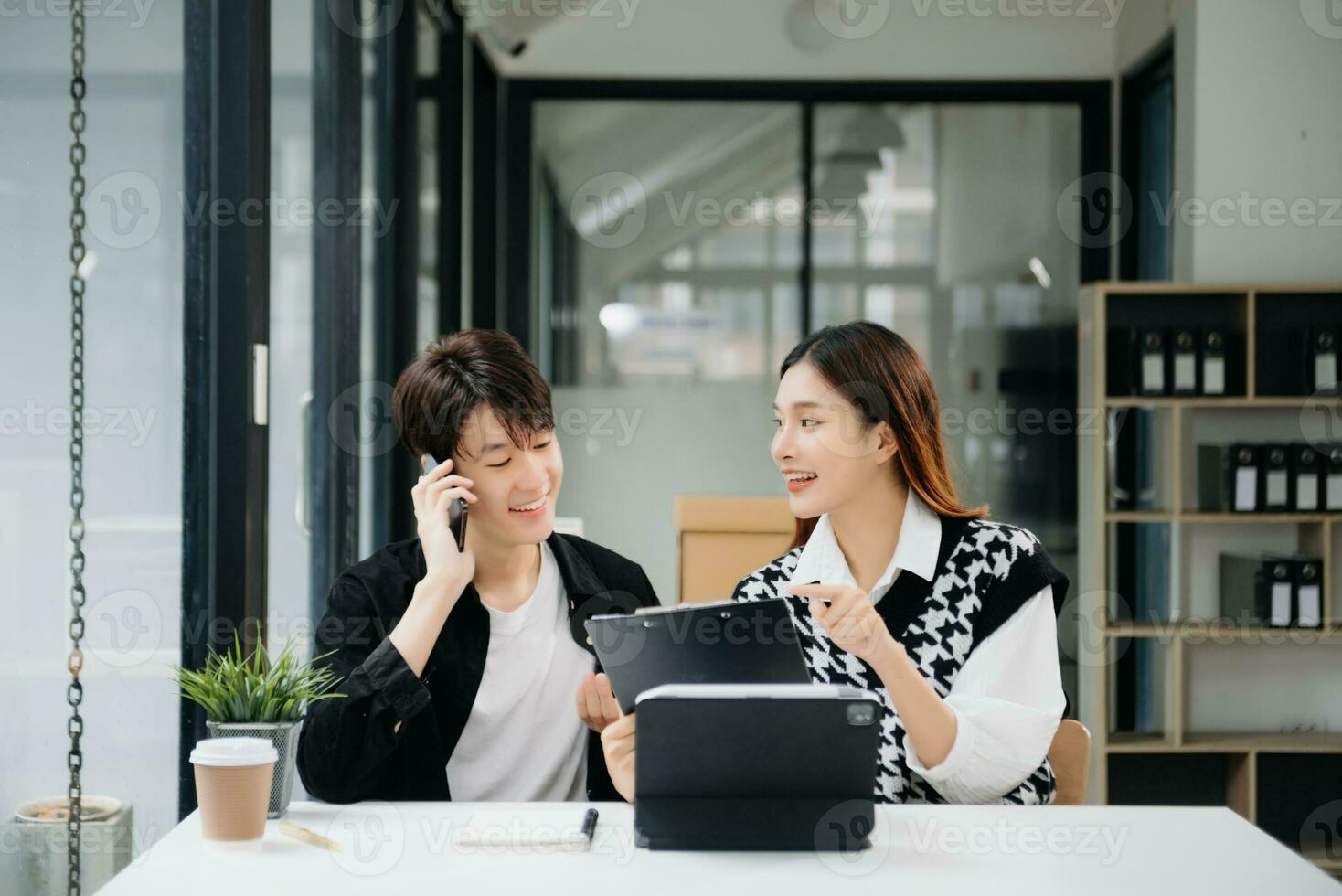 Two Asian businesswoman and man discuss investment project working and planning strategy with tablet laptop computer in office. photo