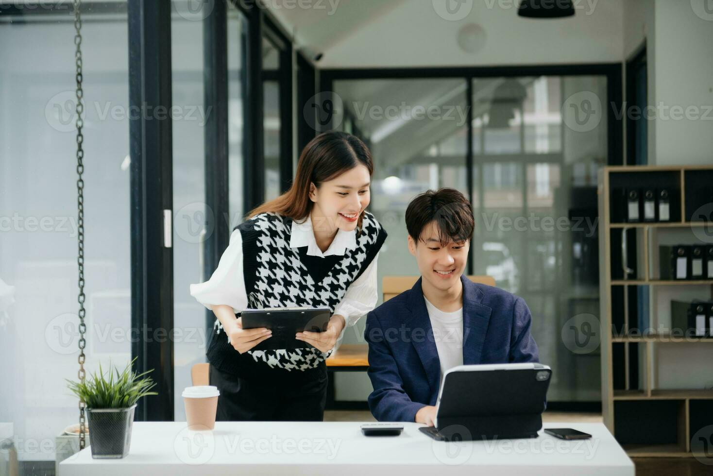 Two Asian businesswoman and man discuss investment project working and planning strategy with tablet laptop computer in office. photo