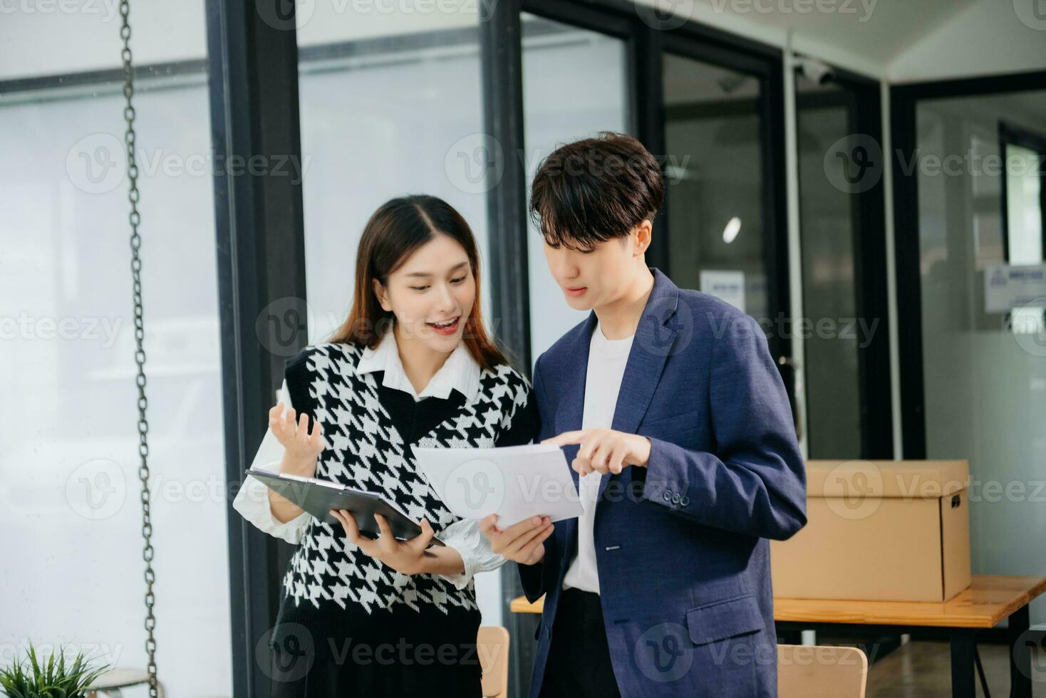 Two Asian businesswoman and man discuss investment project working and planning strategy with tablet laptop computer in office. photo