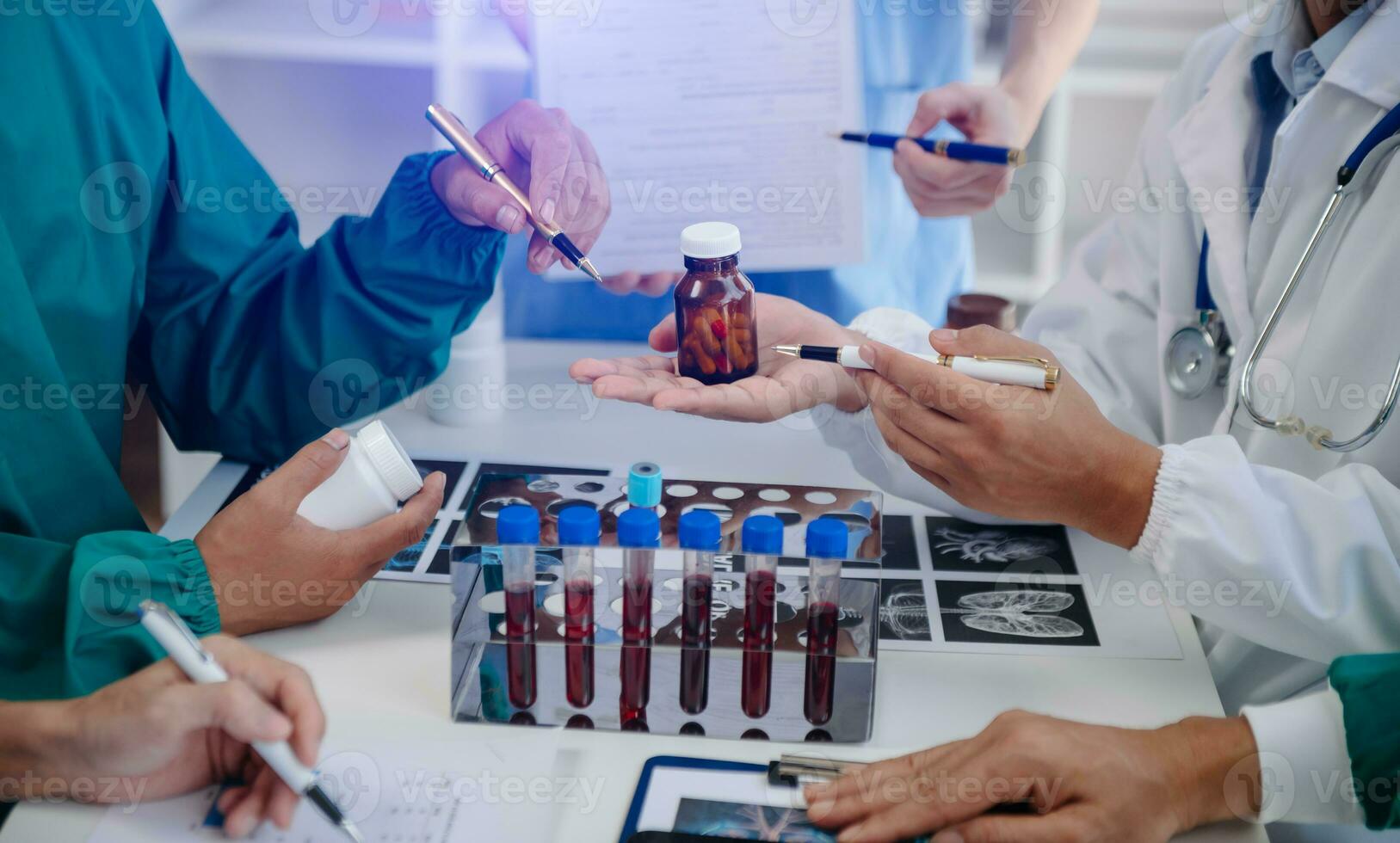 Medical team having a meeting with doctors in white lab coats and surgical scrubs seated at a table discussing a patients working online using computers in the medical industry photo