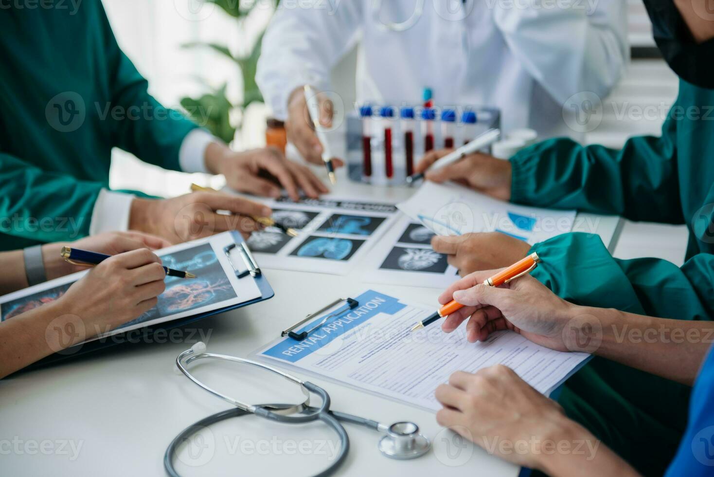 Medical team having a meeting with doctors in white lab coats and surgical scrubs seated at a table discussing a patients working online using computers in the medical industry photo