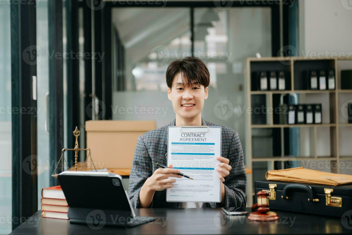 Asian female lawyer chatting online with client on laptop, smartphone  discussing details of lawsuit. in modern office photo
