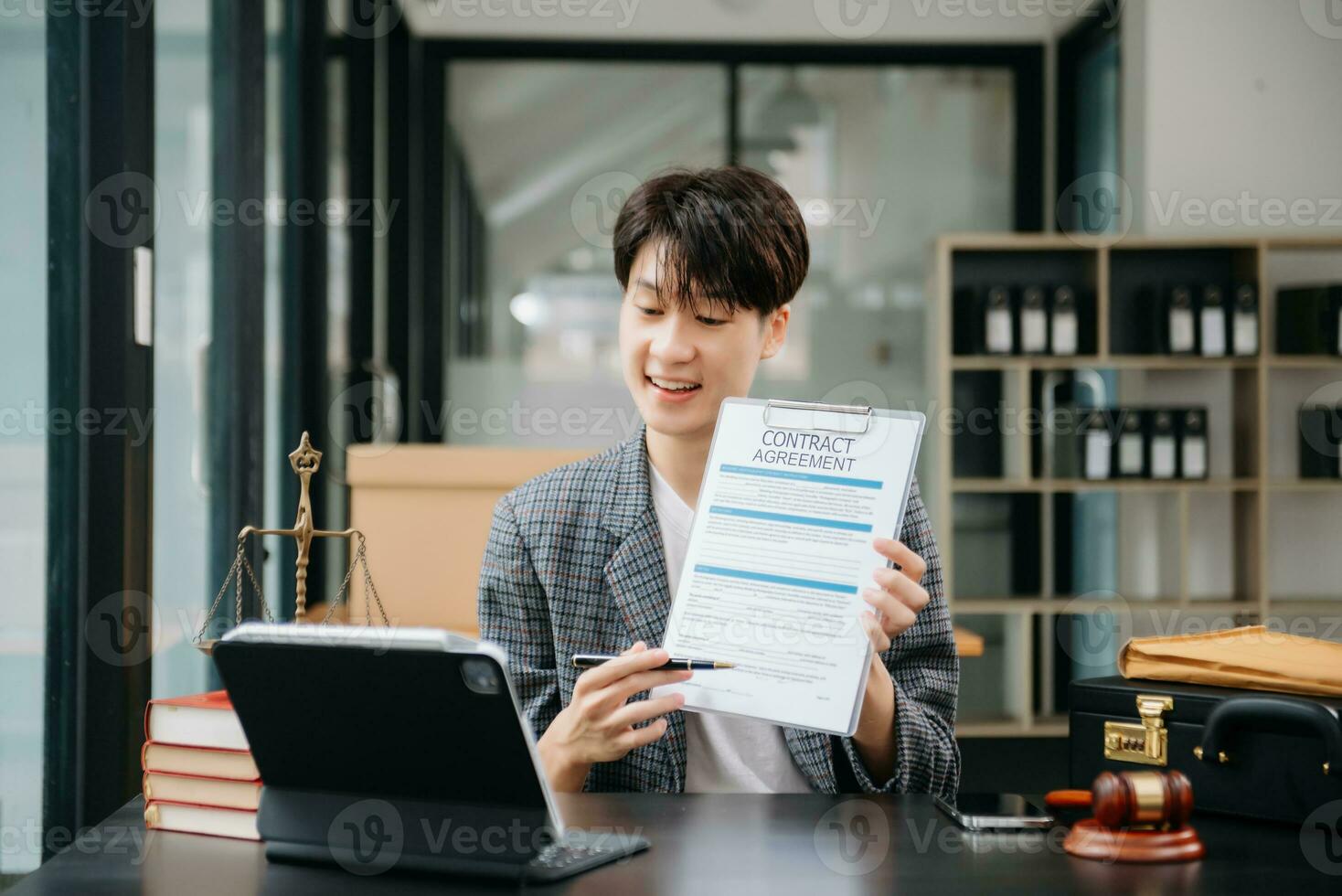 Asian female lawyer chatting online with client on laptop, smartphone  discussing details of lawsuit. in modern office photo