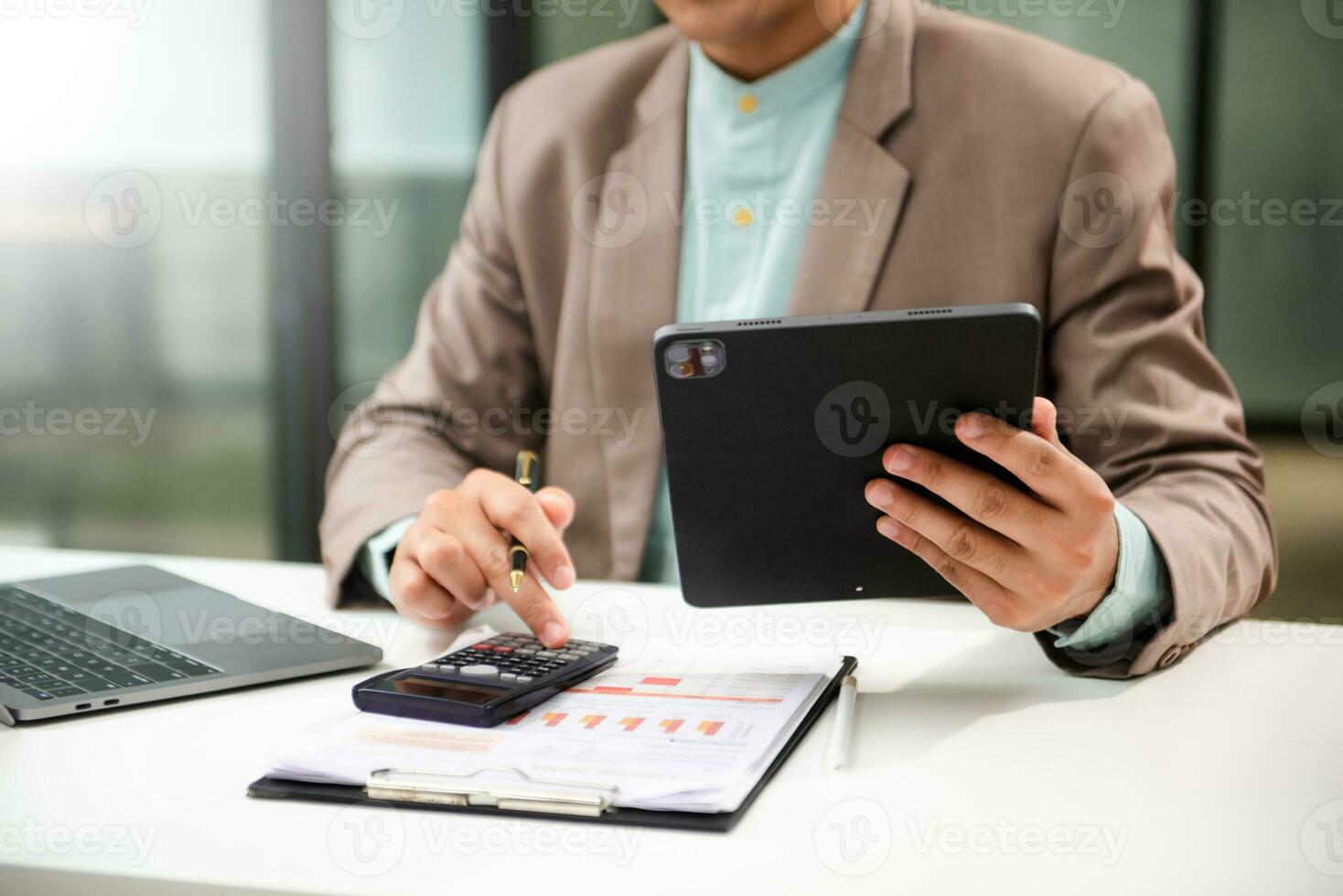 Man counting coins on calculator taking from the piggy bank. hand holding pen working on calculator to calculate on desk about cost at home office. photo