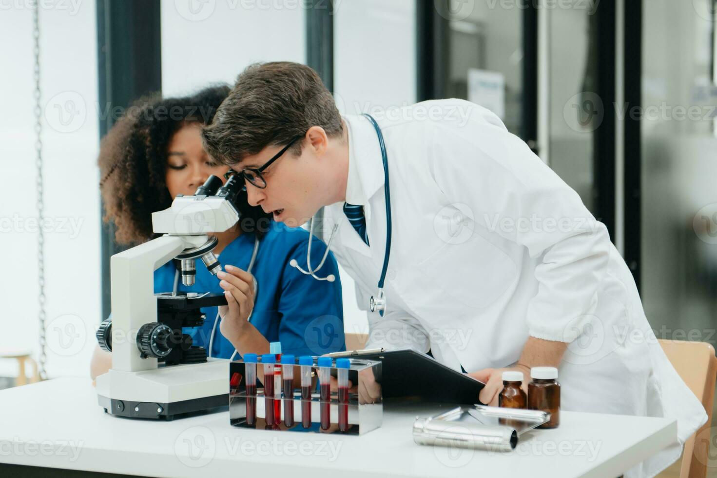 Focused mature male doctor and African female nurse look at tablet and laptop screen discuss anamnesis together. Concentrated diverse medical professionals photo