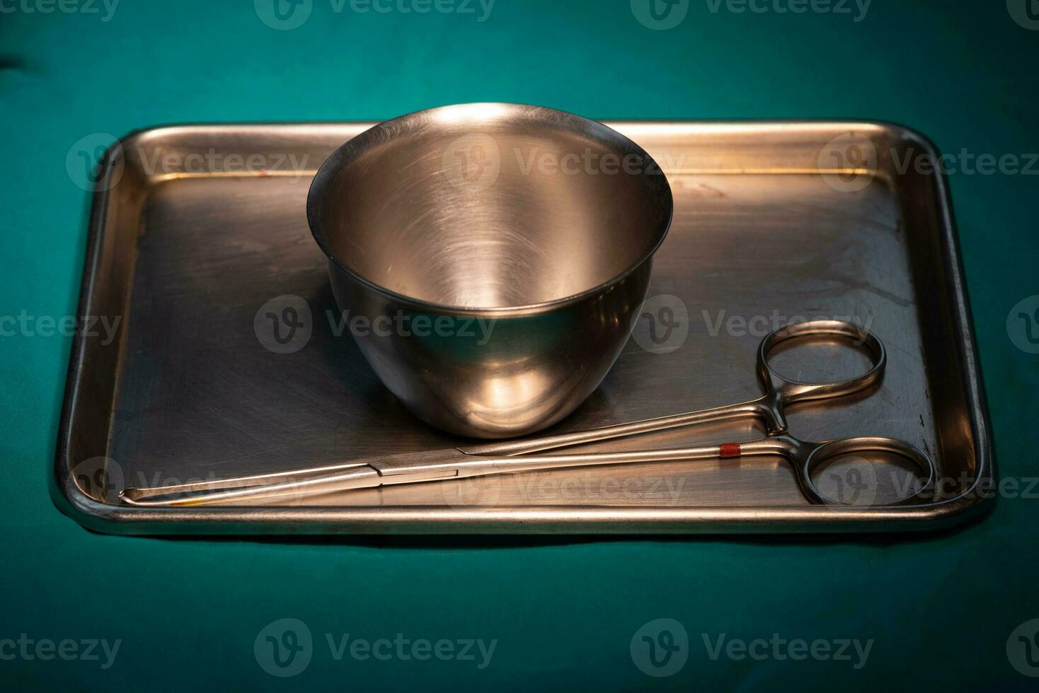 Surgical instruments in silver tray on green table photo