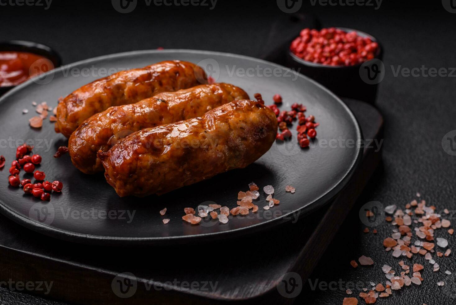 Delicious juicy grilled sausages with salt, spices and herbs photo