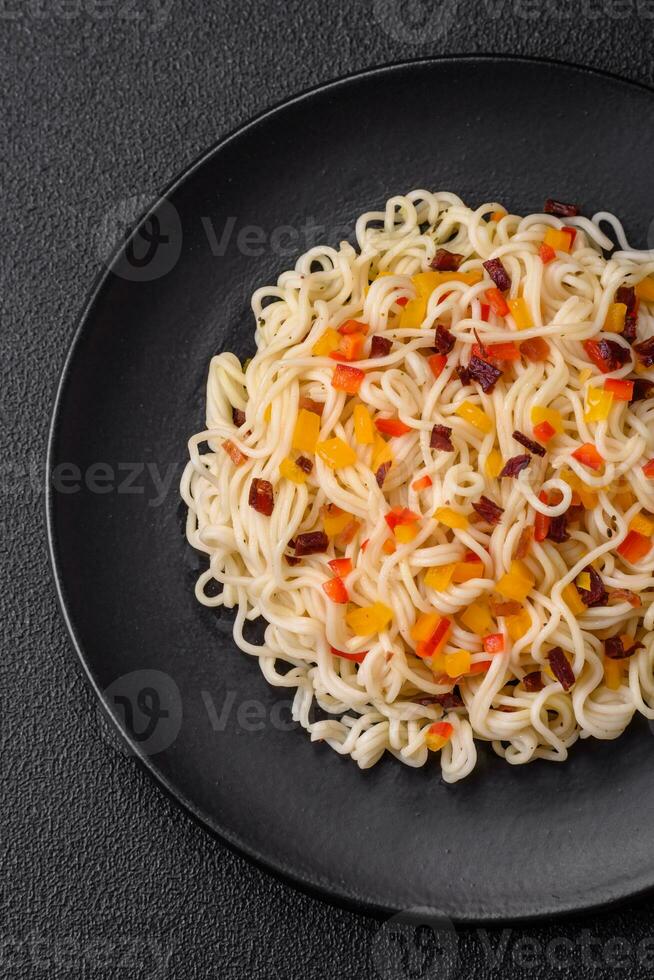 Delicious fresh Asian noodles with pieces of vegetables, meat, with salt, spices and herbs photo