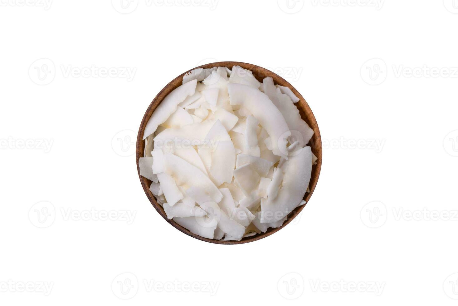 White dry coconut flakes in a wooden bowl prepared for making desserts photo