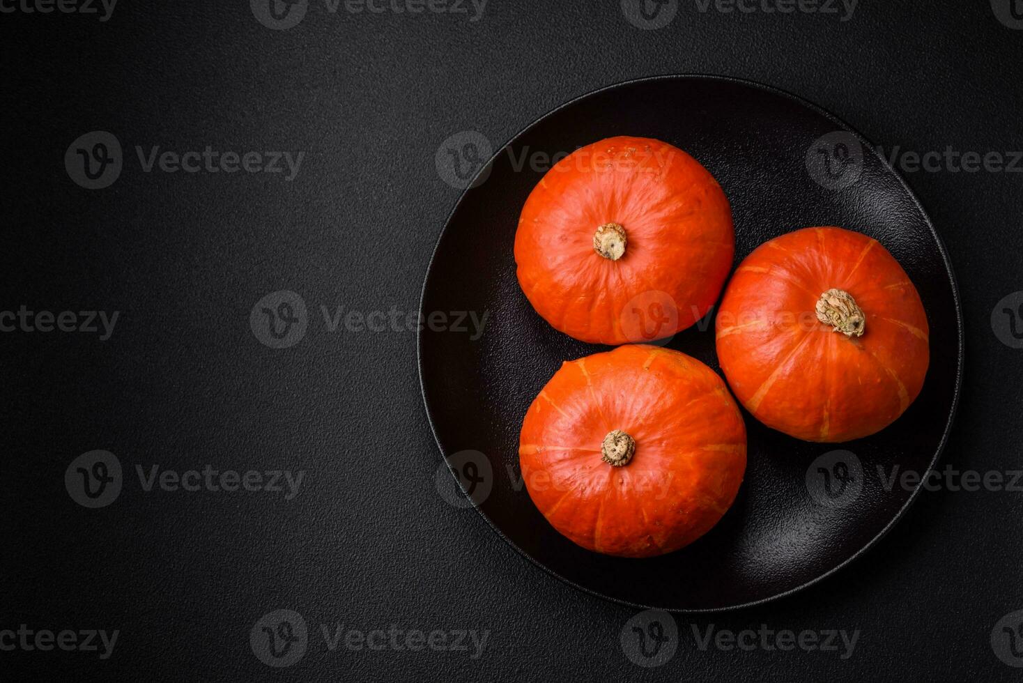 Beautiful fresh round pumpkins in orange color on a dark concrete background photo