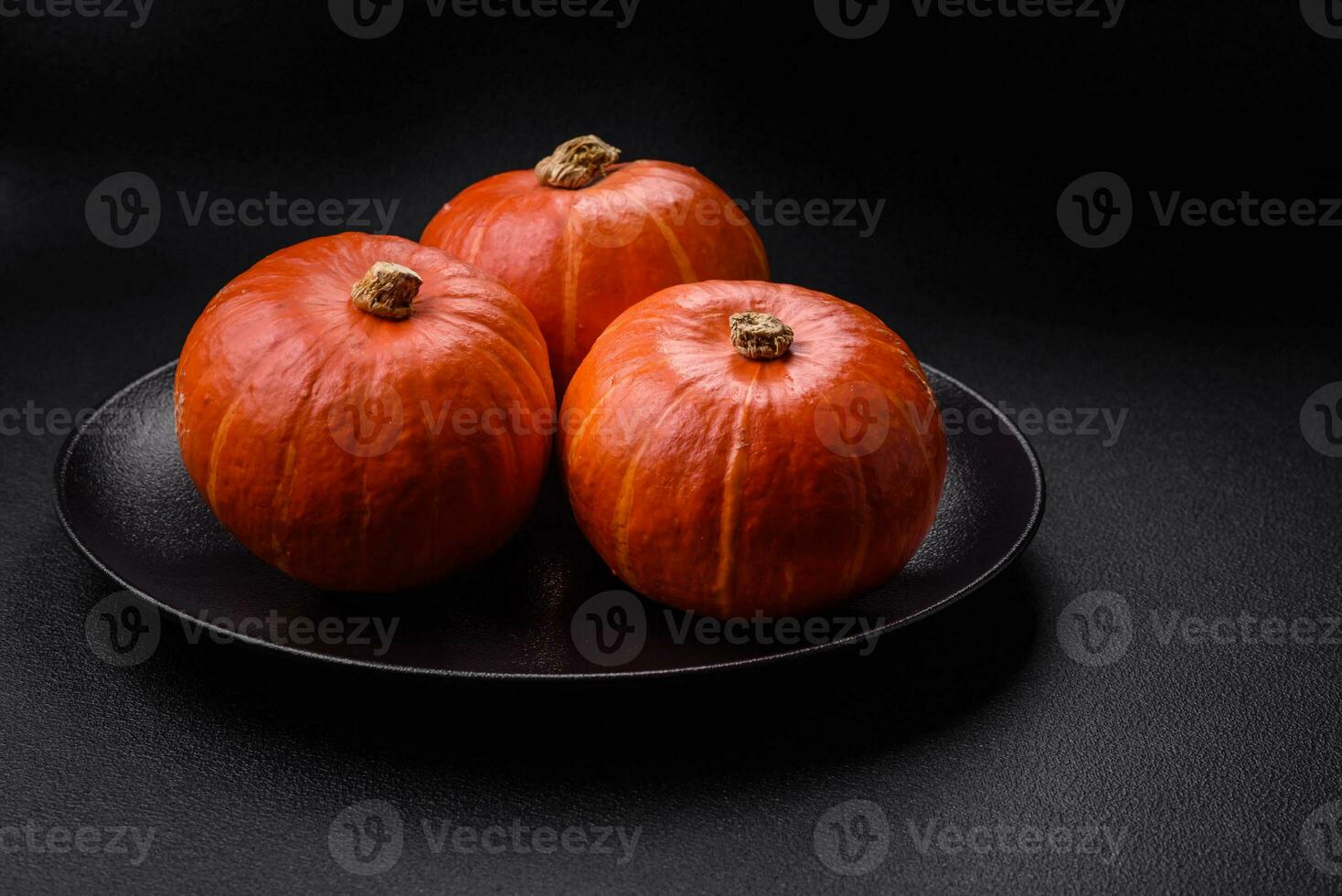 Beautiful fresh round pumpkins in orange color on a dark concrete background photo