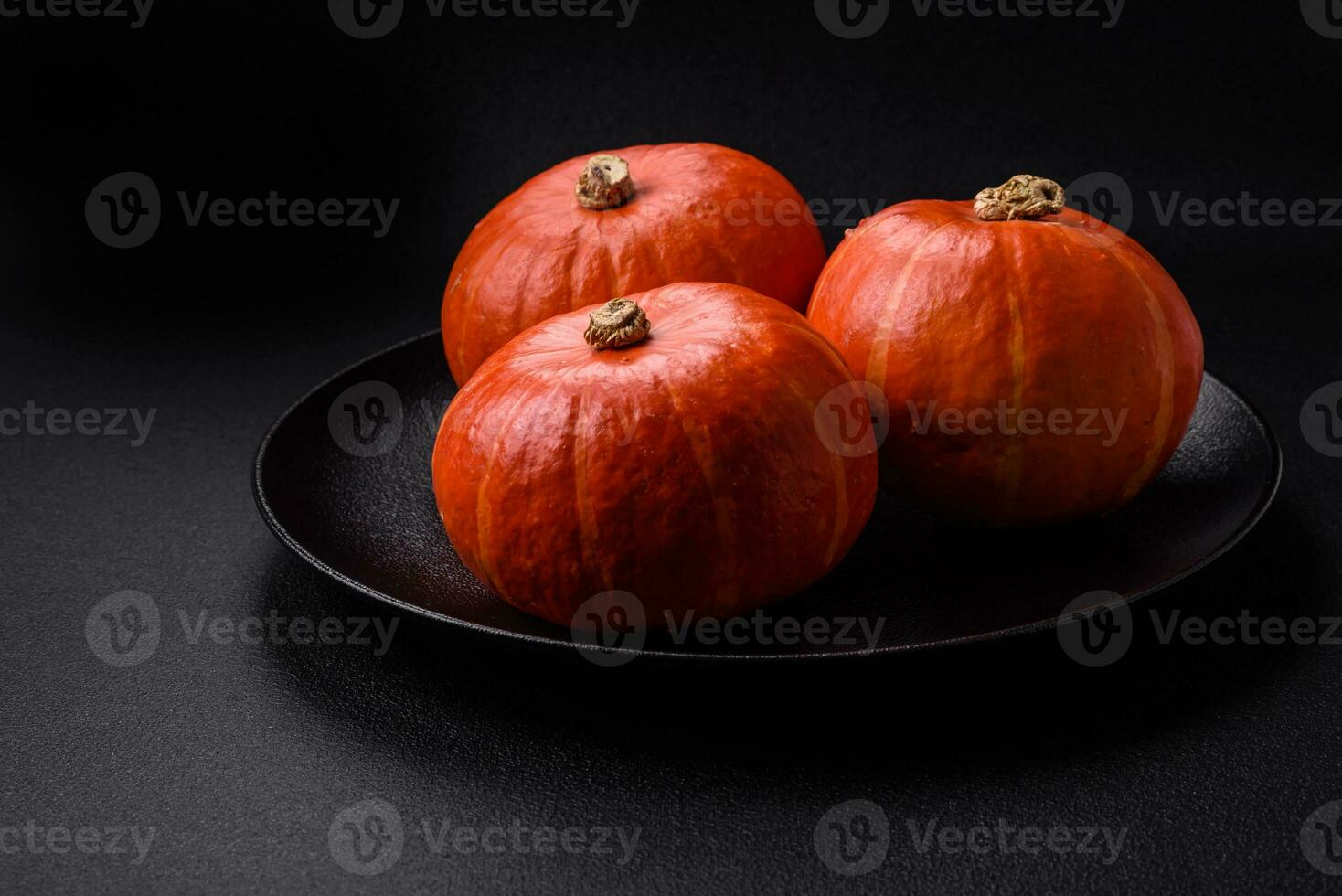 Beautiful fresh round pumpkins in orange color on a dark concrete background photo