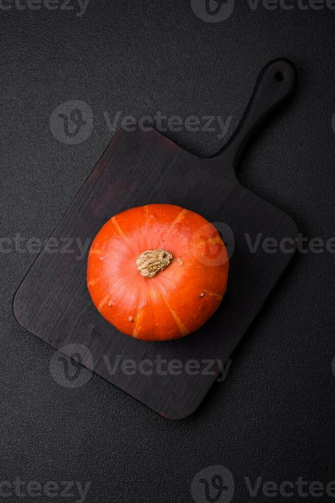 Beautiful fresh round pumpkins in orange color on a dark concrete background photo