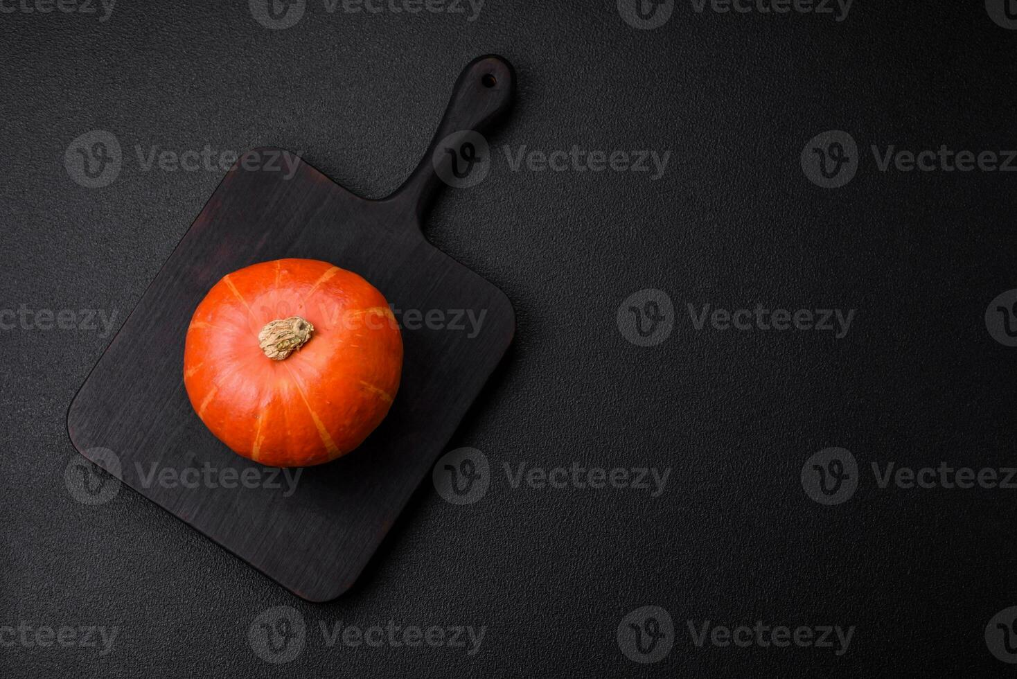 Beautiful fresh round pumpkins in orange color on a dark concrete background photo