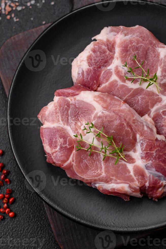 Fresh juicy pork steaks with salt, spices and herbs photo