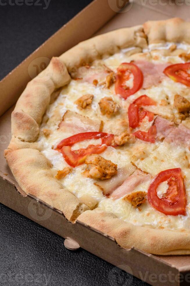 Delicious hot pizza with chicken, tomatoes, cheese and bacon, with salt and spices photo