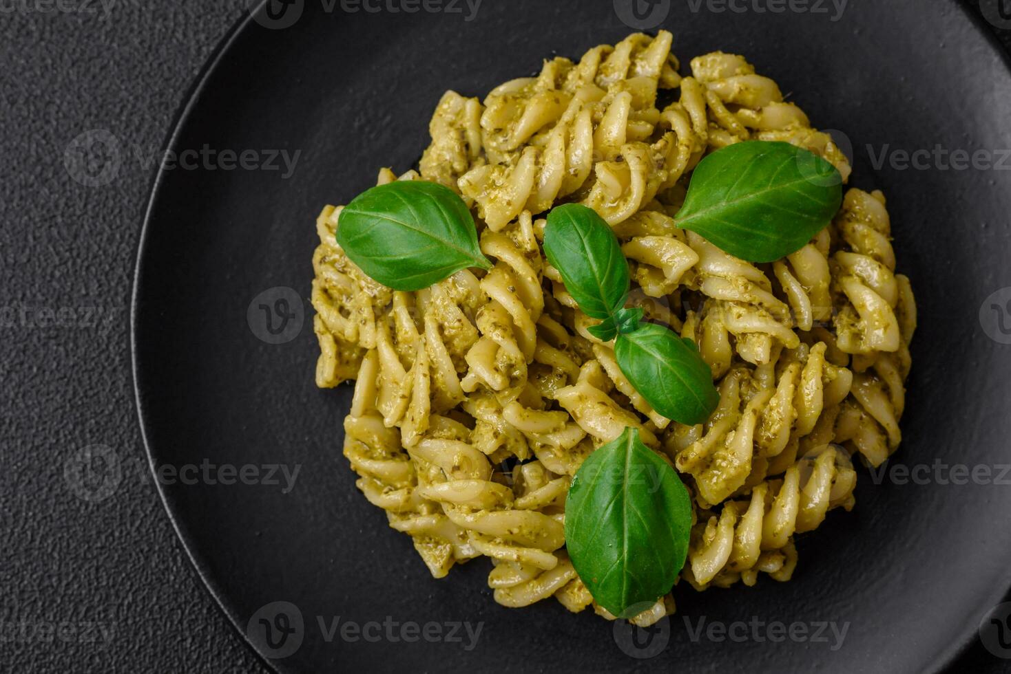 Delicious fresh pasta with green pesto sauce with basil photo