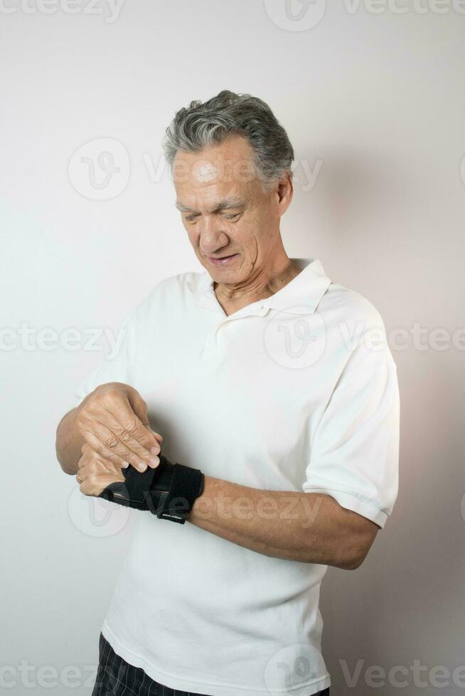 Senior Man wearing a wrist brace on his left hand and wrist for pain management photo