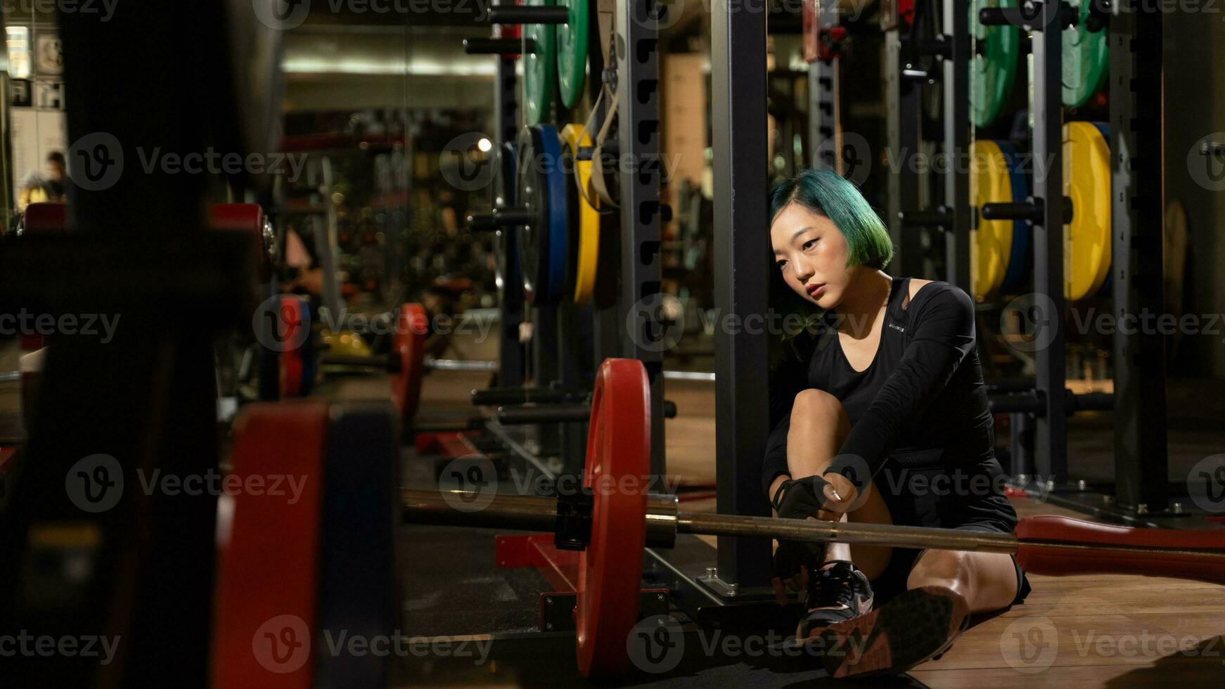 Beautiful sporty woman resting tired after lifting barbell on a muscular training in fitness center photo